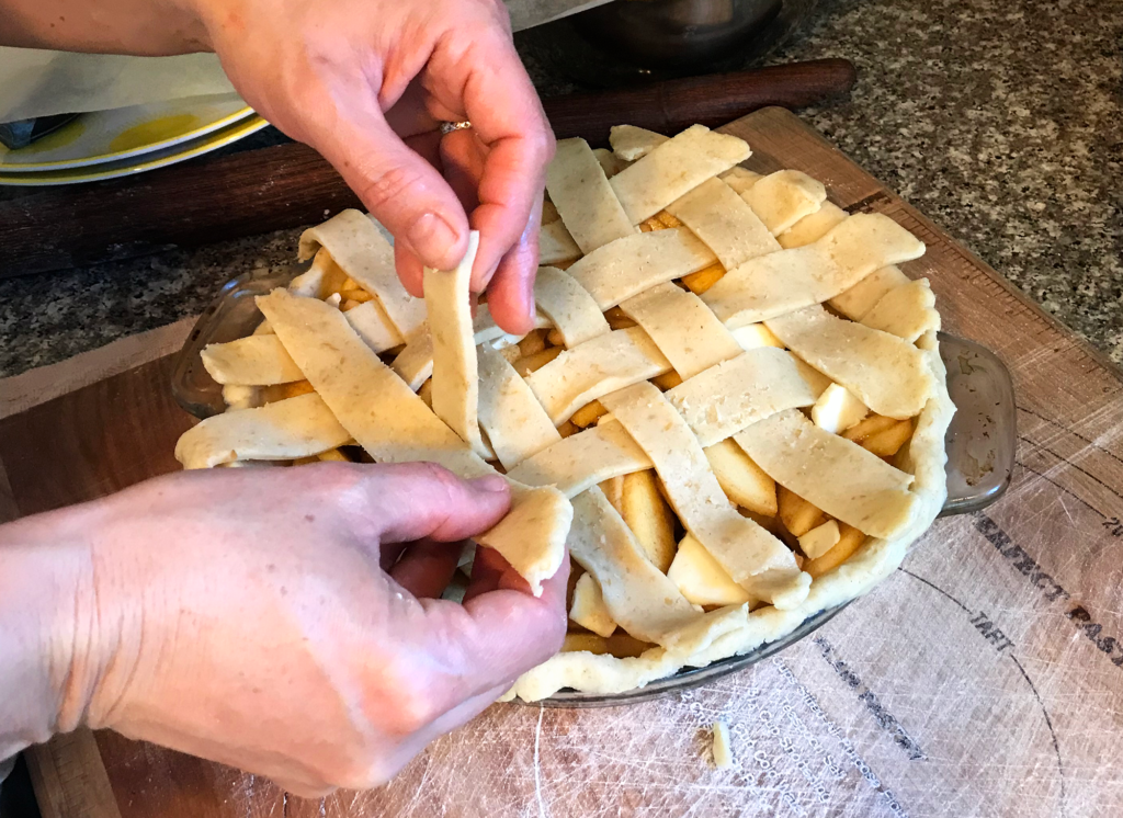 woman arranging lattice crust for apple pie
